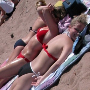 Cute teens tanning in bikinis at the beach
